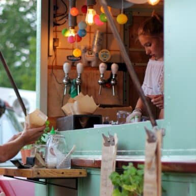 Jeune fille qui prépare une commande à bord d'un foodtruck vert pâle