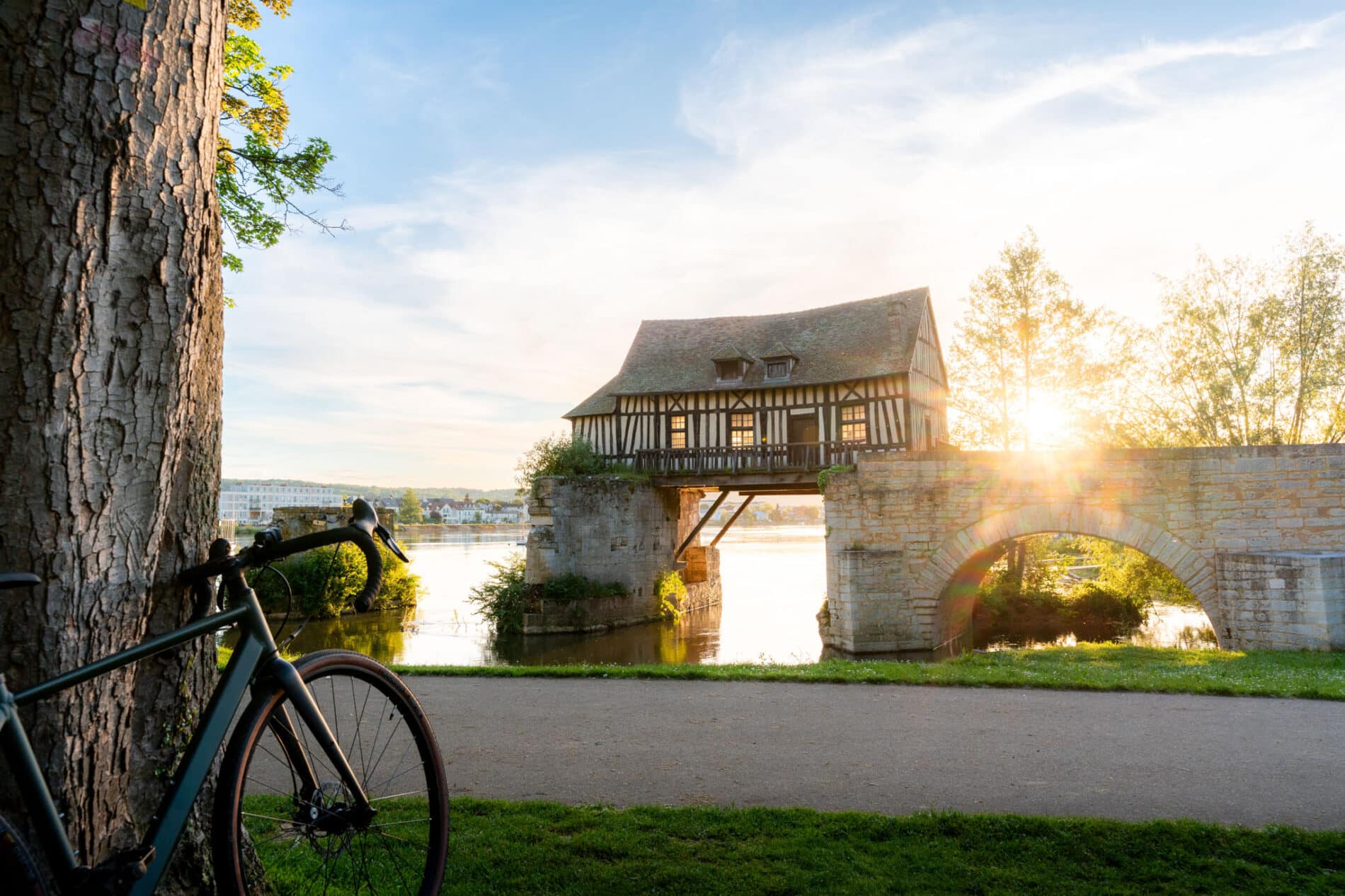 Vernon, le Vieux Moulin avec un coucher de soleil en arroière plan et un vélo au premier plan